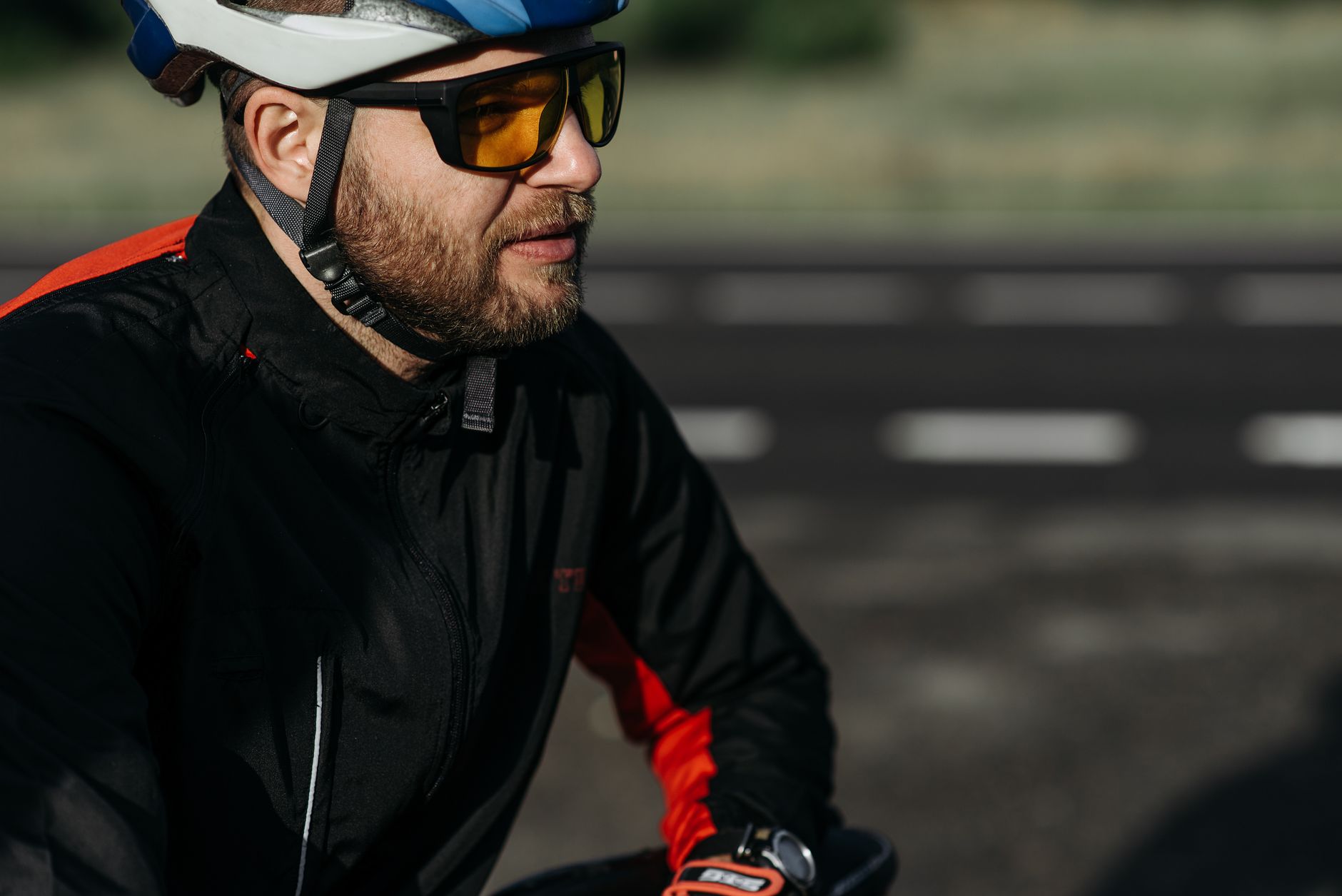 Mężczyzna w niebiesko-białym kasku rowerowym i żółtymi sportowymi okularami