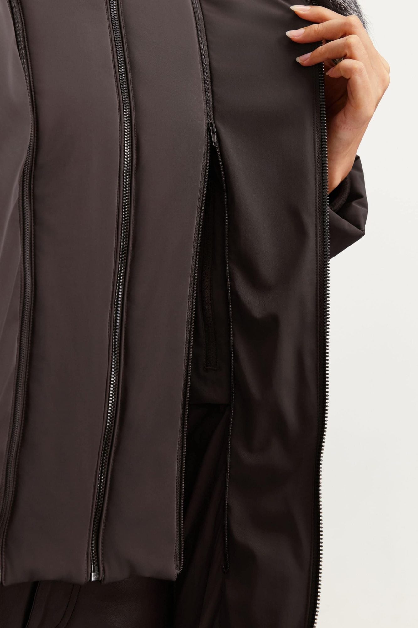 Close-up detail of brown puffer jacket showing vertical quilted seams and zippers down the front panels