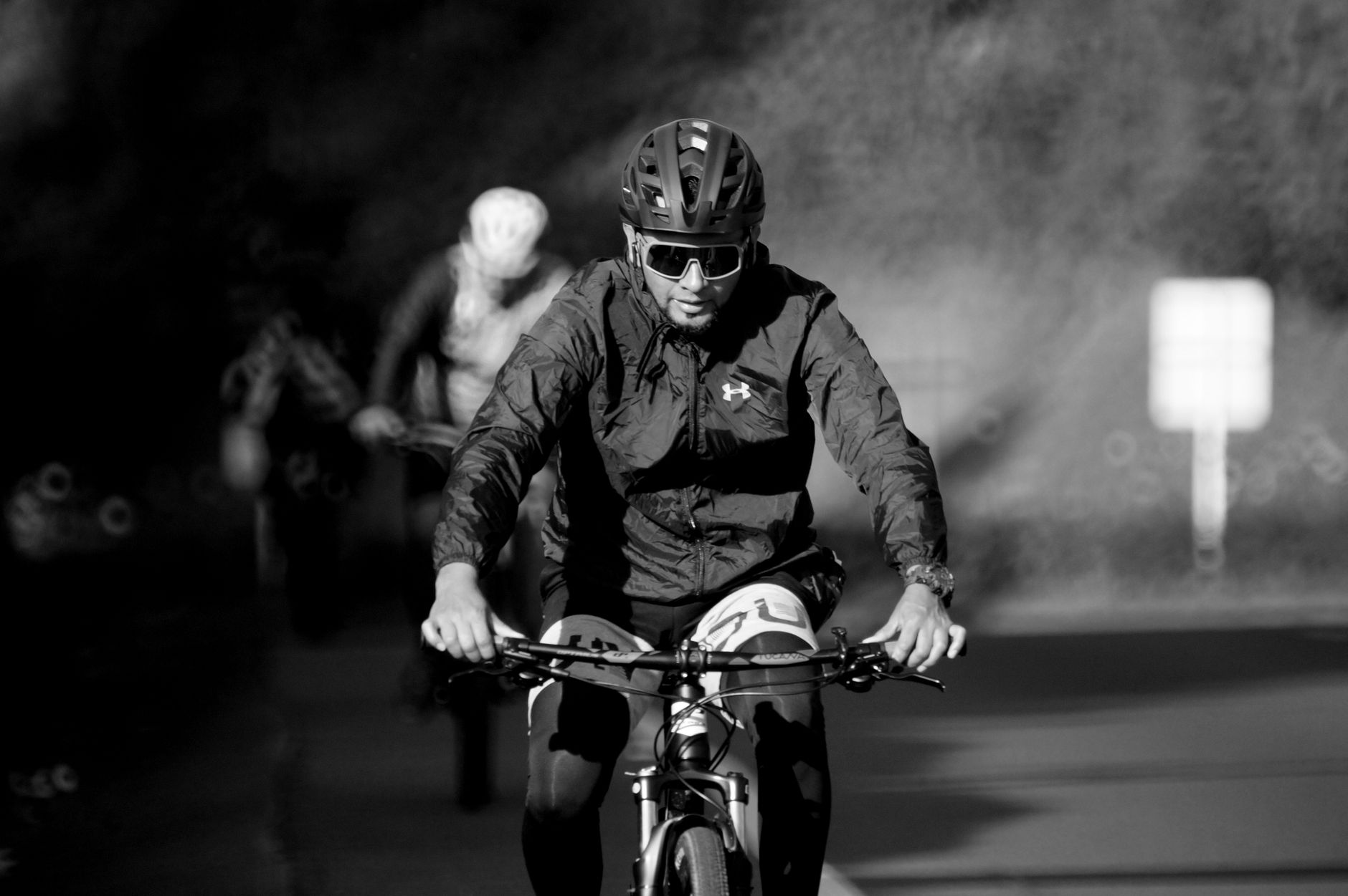 Rowerzysta nocą w czarnej kurtce i kasku jeżdżący na rowerze